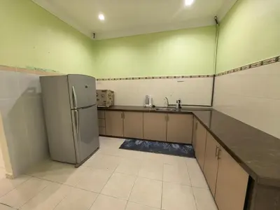 a kitchen with a refrigerator and a sink at Lagenda Serai Wangi Homestay in Padang Serai