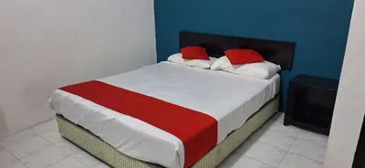 a bed with two red pillows on it in a room at Captain Hotel Cafe & Bistro in Sitiawan
