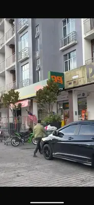 a man pushing a car parked in front of a building at Lily Studio in Brinchang