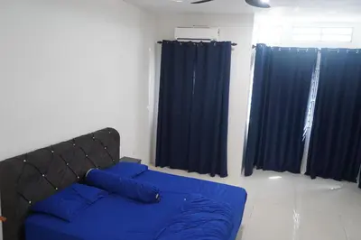 a bed with blue pillows in a room with blue curtains at Homestay Behrang Sentral in Kampung Behrang