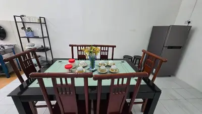 a dining room table with chairs and a refrigerator at Anjung Vacation Home No 70 in Gua Sai
