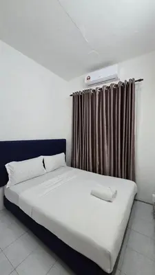 a bedroom with a large white bed with a window at Anjung Vacation Home No 70 in Gua Sai