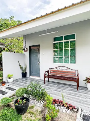 a bench on a wooden deck in front of a house at NAR Kampung Studio in Bayan Lepas