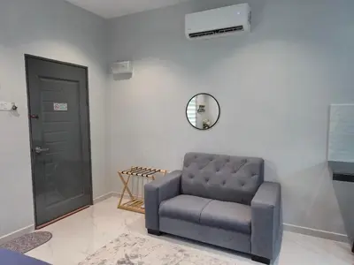 a gray chair sitting in a room with a mirror at NAR Kampung Studio in Bayan Lepas