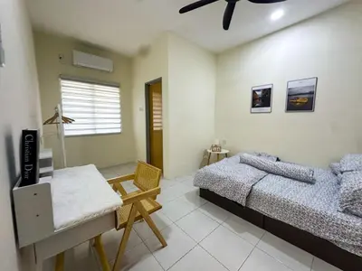 a bedroom with two beds and a table and a chair at Hana Homestay Seri Iskandar in Seri Iskandar