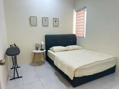 a bedroom with a bed with a black headboard and a table at Hana Homestay Seri Iskandar in Seri Iskandar