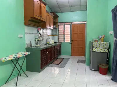 a kitchen with green walls and a red door at Anuarosi Homestay Taman Melor, Teluk Intan in Teluk Intan