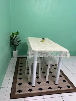 a white table with two white chairs on a rug at Anuarosi Homestay Taman Melor, Teluk Intan in Teluk Intan