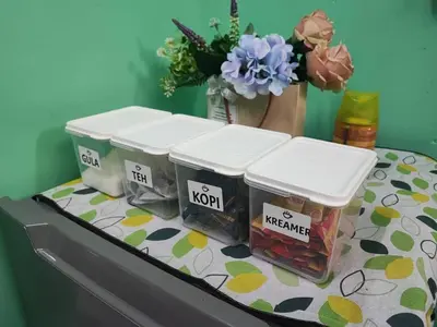 three containers of jam sitting on a table with flowers at Anuarosi Homestay Taman Melor, Teluk Intan in Teluk Intan