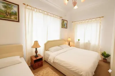 a bedroom with a white bed and a window at Holiday Bungalow Guesthouse in Tanah Rata