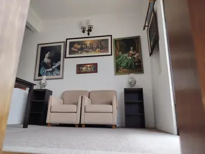 a living room with a couch and paintings on the wall at Holiday Bungalow Guesthouse in Tanah Rata