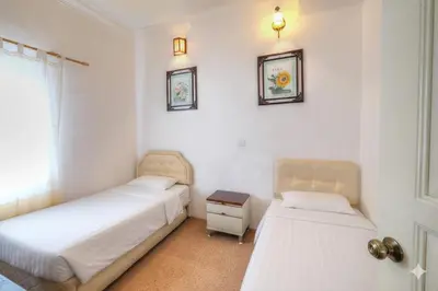 a bedroom with two beds and a table and two mirrors at Holiday Bungalow Guesthouse in Tanah Rata