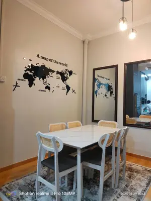 a table with chairs and a map of the world on a wall at Homestay Saujana Hill in Gua Musang