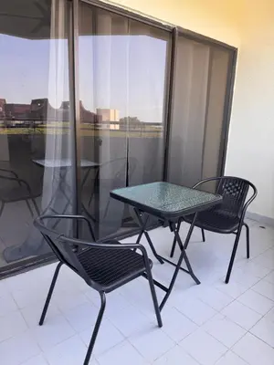 a glass table and two chairs on a balcony at Sri Sayang sunset 2 bedroom in Batu Ferringhi