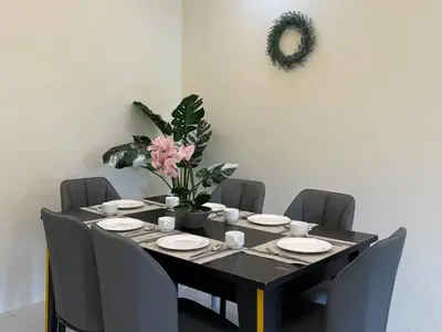a dining room table with chairs and a table with pink flowers at Cozy 3BR Emerald Avenue Brinchang, 8pax Netflix in Brinchang