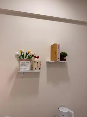 a white wall with two shelves with flowers on it at Cozy Inn Homestay in Kampar
