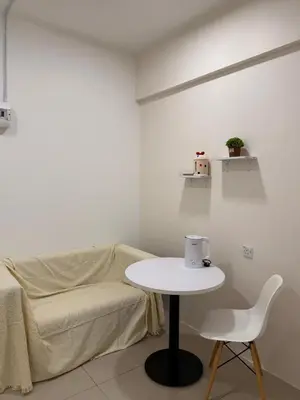 a white living room with a table and a couch at Cozy Inn Homestay in Kampar