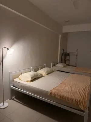 two beds in a bedroom with a lamp and a bedskirtspectspectspectspects at Cozy Inn Homestay in Kampar
