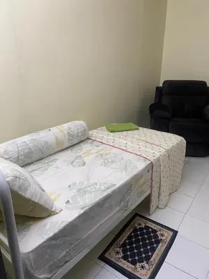 two beds in a room with a couch and a table at Mumtaz Homestay in Kampong Belah Dua