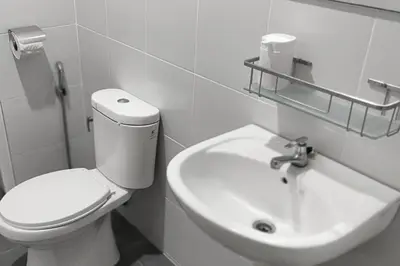 a white bathroom with a toilet and a sink at Majestic Sanctuary Homestay Taiping with Netflix - 2 Carpark in Taiping