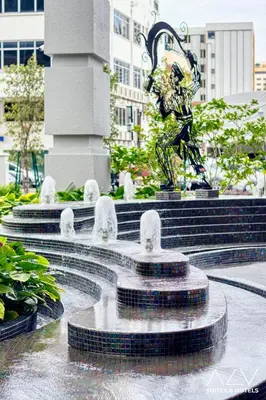 a statue of a man sitting on top of a fountain at 22 Macalisterz by ALV in George Town