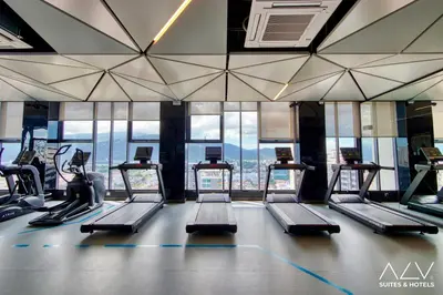 a gym with treadmills and ellipticals in front of windows at 22 Macalisterz by ALV in George Town