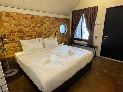 a bedroom with a large white bed with a brick wall at Miner's House Ipoh in Ipoh
