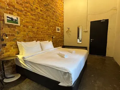 a large bed in a room with a brick wall at Miner's House Ipoh in Ipoh
