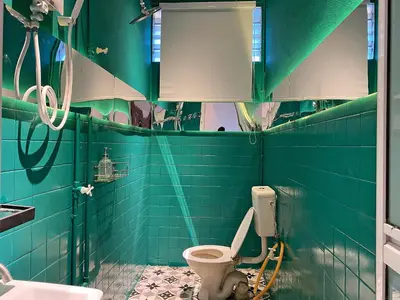 a bathroom with green tiled walls and a toilet at The Nook Holiday Home Cozy, Stylish, Swimming Pool in Ipoh