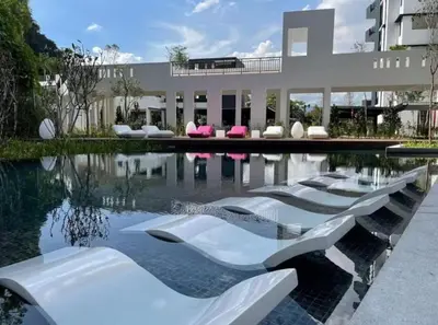 a pool of water with white chairs and a building at The Cove 4-7 pax in Ipoh