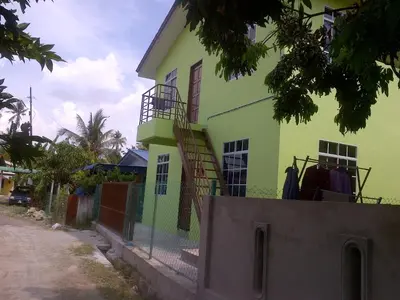 a lime green house with a staircase in front of it at Penang Green Homestay in Permatang Pauh