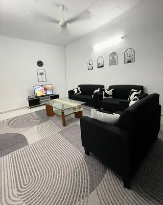 a living room with two black couches and a tv at Homestay Bonda F in TanjongMalim