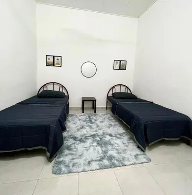 two beds in a room with a rug at Homestay Bonda F in TanjongMalim