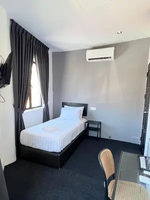 a bedroom with a bed and a table and a window at Quee Hotel in George Town