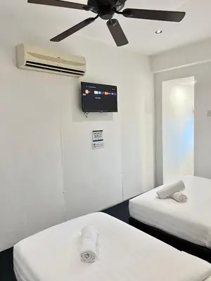 a room with two beds and a ceiling fan at Quee Hotel in George Town