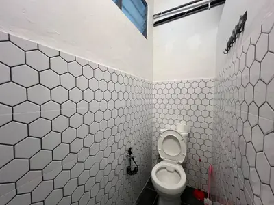 a bathroom with a toilet and a white tiled wall at Vintage Comfort 3Bedroom Haus in Lunas