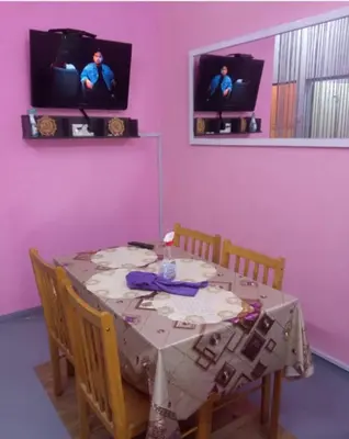 a dining room with a table and a pink wall at Homestay Bajet IPOH in Ipoh