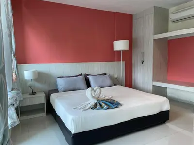 a bedroom with a white bed with a red wall at Homestay Marina in Lumut