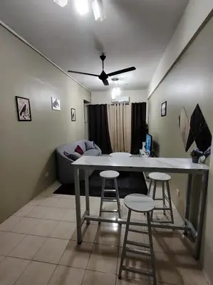 a living room with a table and two bar stools at Firza Suite in Gua Sai