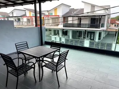 a table and chairs on a balcony with a house at 38G Homestay in Teluk Intan