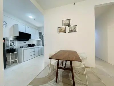 a kitchen with a wooden table and white walls at Aston Acacia Homestay in Bukit Mertajam