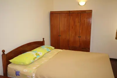 a bedroom with a bed and a wooden cabinet at Eden Seaview in Batu Ferringhi