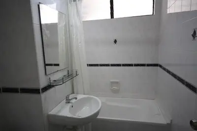 a white bathroom with a sink and a bath tub at Eden Seaview in Batu Ferringhi