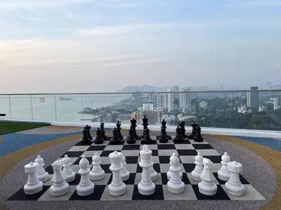 a chess board on a ledge with a view of a city at Georgetown 2BR Luxury Condo Unbeatable Night View Infinity Pool Attractions Food Fully Equipped#148B in Bayan Lepas