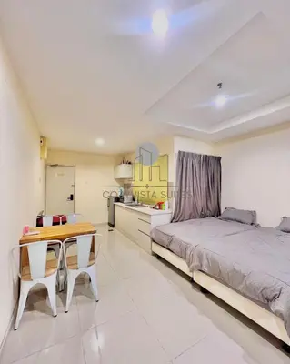 a bedroom with a bed and a table and a kitchen at CozyVista Suites Marina Island Lumut Perak in Gua Sai