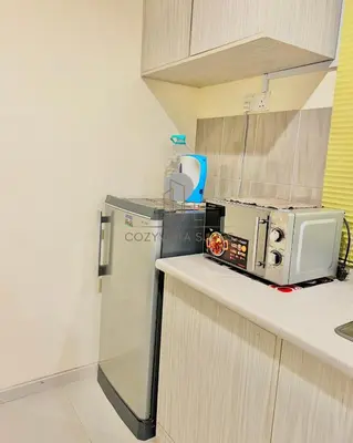 a kitchen with a microwave and a refrigerator at CozyVista Suites Marina Island Lumut Perak in Gua Sai
