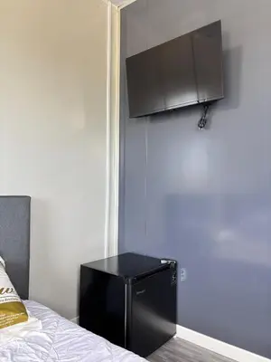 a small black refrigerator in a room next to a bed at Roomstay Kontena Sungai Bioh in Gua Sai