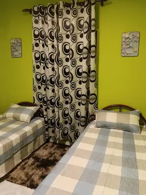 two beds in a room with green walls and a curtain at Homestay Bonda D' in TanjongMalim