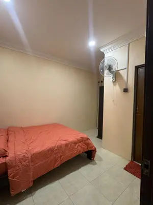 a bedroom with a red bed and a fan at Homestay NIA Chukai in Gua Sai