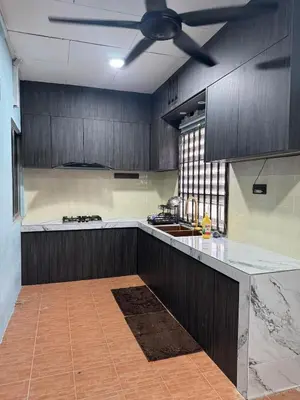 a kitchen with wooden cabinets and a ceiling fan at Homestay NIA Chukai in Gua Sai